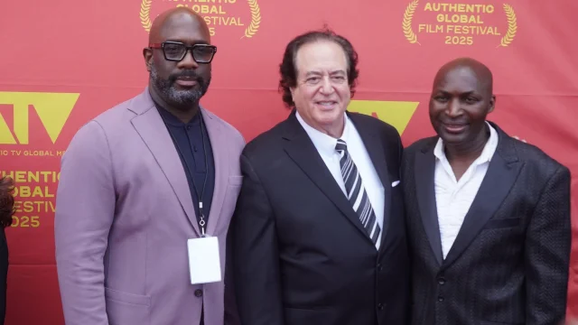 Three filmmakers posing in front of the festival backdrop at the 2025 festival