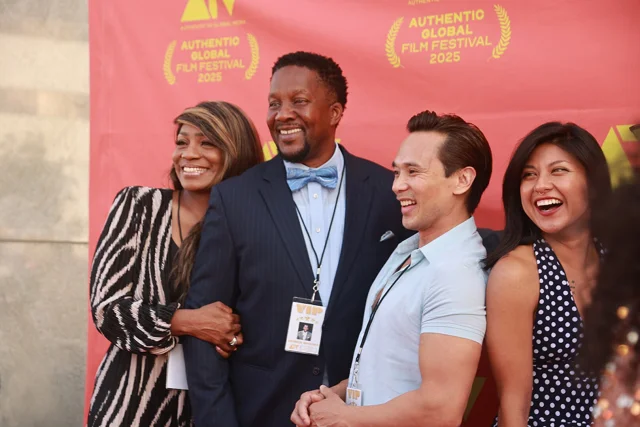 Four smiling guests posing on the red carpet in front of the festival backdrop